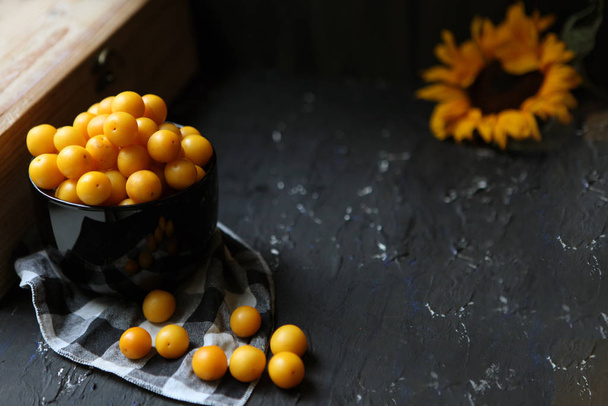 gelbe Pflaumen mit Zitrone und Limette auf schwarzem Hintergrund. Zutaten für eine Marmelade. Foodfotografie. gelbe Sonnenblume, Herbstkonzept, - Foto, Bild