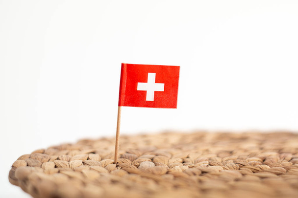 Small Swiss flag on a toothpick pinned on a knitted hemp kitchen - Zdjęcie, obraz