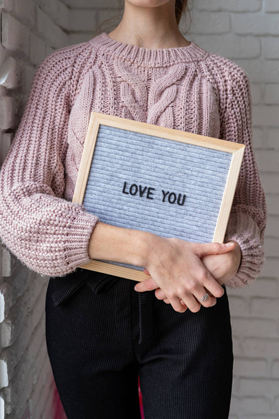 Νεαρή γυναίκα που κρατά τον πίνακα με τις λέξεις "Σ 'αγαπώ" - Φωτογραφία, εικόνα