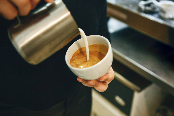 Barista pours milk into coffee - Foto, imagen
