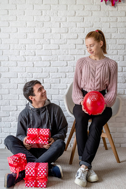 Young couple with gifts and balloons looking at each other - Фото, зображення