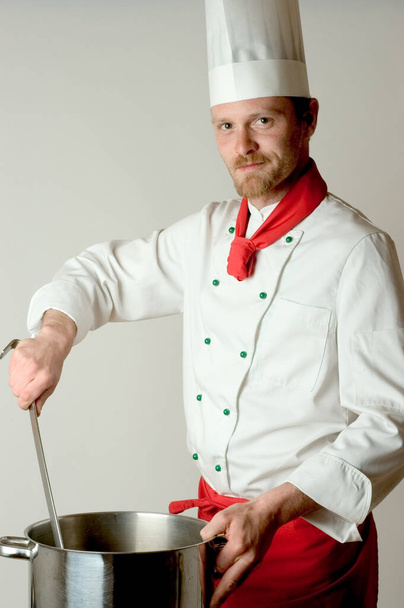 chef in uniform met een koekenpan op de keuken - Foto, afbeelding