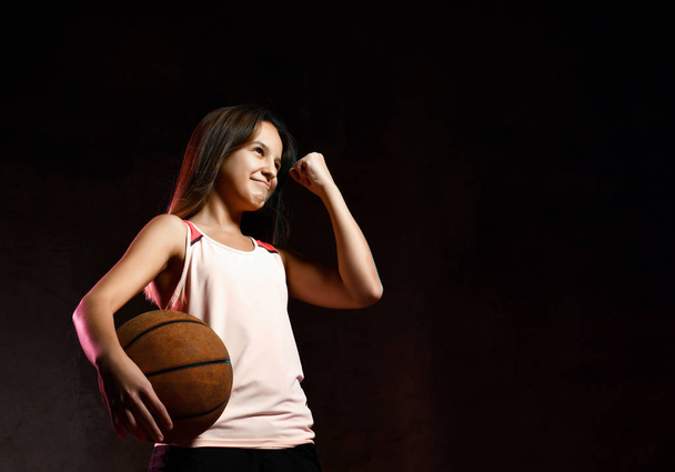 Beautiful caucasian teen woman in sportswear playing basketball . Sport concept isolated on black background. - Foto, Imagem