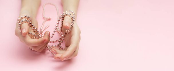 Concept de victime de la mode plat couché sur un fond rose. Shopaholics femmes mains liées avec une corde avec des perles. Trouble de l'achat compulsif
. - Photo, image