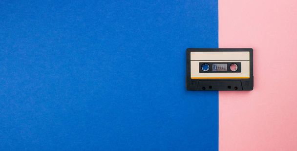 Retro audio kaseta płaska leżała na kolorowym niebieskim różowym pastelowym tle. Widok z góry z miejsca kopiowania. Kreatywne projektowanie mody w minimalnym stylu 80-tych z duotonami. Muzyka, radio, koncepcja DJ-a. Wzór banera - Zdjęcie, obraz