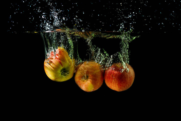 Tre mele che schizzano in acqua su fondo nero
. - Foto, immagini