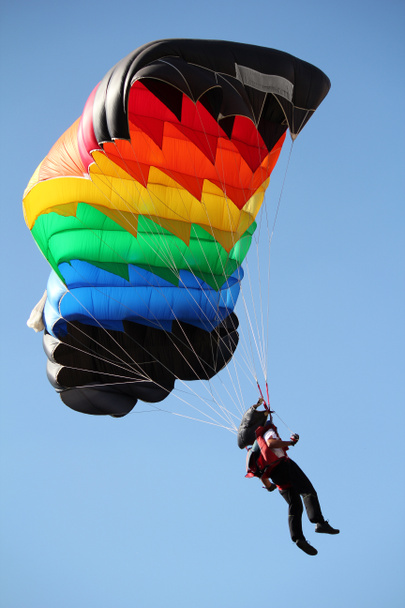Fallschirmspringer mit buntem Fallschirm am blauen Himmel - Foto, Bild