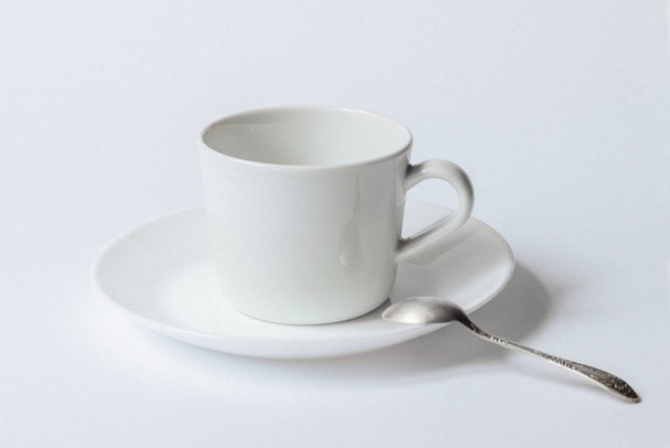 weiße Kaffeetasse auf Teller und Teelöffel isoliert auf weißem Hintergrund - Foto, Bild