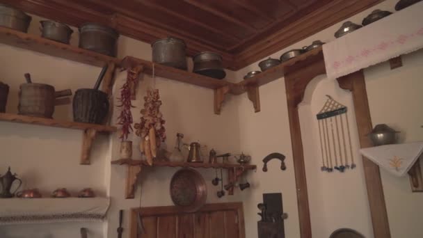 Kitchen of a poor village house. Old wooden home interior. Antique household items. Pot pots coffee mill colander sieve skimmer perforated ladle. Stuff tools. Dried pepper and corn hanging on rope. 4K - Footage, Video