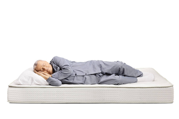 Elderly man in pajamas sleeping on a bed mattress  - Photo, Image