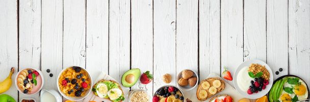 Banner de comida saludable para el desayuno con borde inferior. Escena de mesa con fruta, yogur, batido, tostadas nutritivas, cereales y sartén de huevo. Vista superior sobre un fondo de madera blanca. Copiar espacio
. - Foto, imagen
