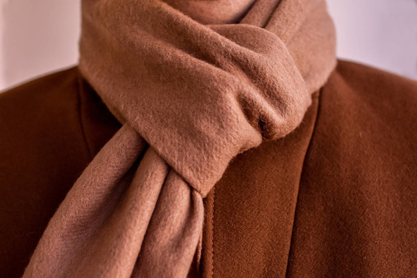 Close up of light beige scarf combined with fashionable mens brown coat. Низкий уровень. Селективный фокус
. - Фото, изображение