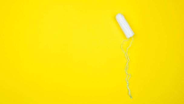 White clean cotton tampon on bright yellow background. Menstrual cycle colorful flat lay. Critical days and menstruation concept. Female hygiene. Woman menstruation. Stock photo - Photo, Image