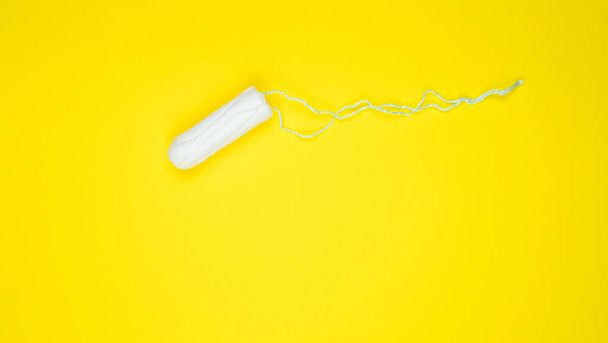 Hygienic white tampon for women. Cotton swab. Menstruation, means of protection. Tampons on a yellow background - 写真・画像