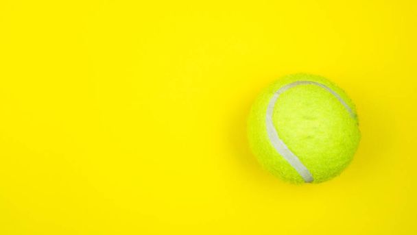 Tennis ball isolated on yellow background - Foto, Imagen