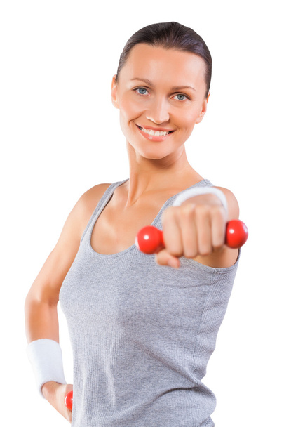 A sports female holding dumbbell and smiling isolated - Foto, imagen