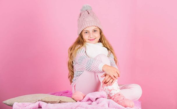 Child long hair warm woolen hat enjoy warm. Warm clothes concept. Keep warm and comfortable. Warm accessories that will keep you cozy this winter. Kid girl wear knitted hat relaxing pink background - Photo, image
