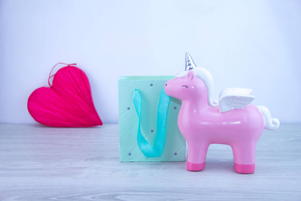 Toy and gift bag. Unicorn on a light background. Partial focus - Photo, image