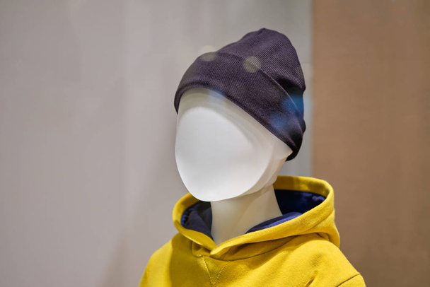 Bust of a baby mannequin in a hat and a yellow jumper. - Photo, Image