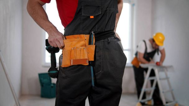 Un joven trabajador que se pone un cinturón de herramientas
 - Foto, imagen