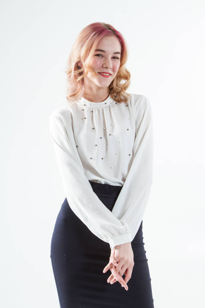 白いセーターと暗いスカートの若いブロンド。白い背景のスタジオポートレート - 写真・画像