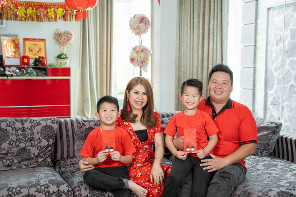 Asian family with two son holding ang pao smiling looking at camera - Фото, изображение