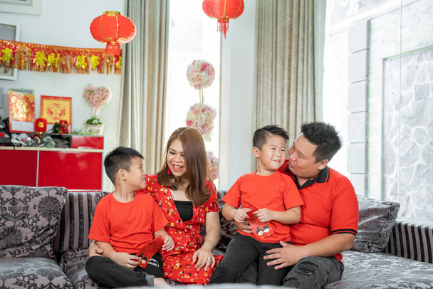 Asian family with two son holding ang pao chatting together - Foto, immagini