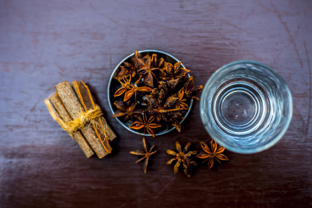 Face mask for wrinkles on the wooden surface consisting of some cinnamon sticks, water, and star anise seed powder. - Foto, Bild