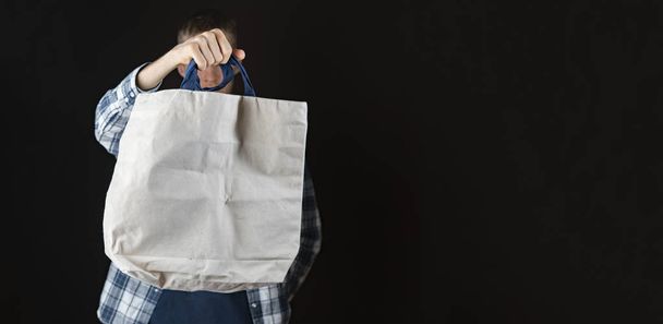 χέρι κρατώντας ένα κενό μονόχρωμο υφασμάτινη τσάντα με χώρο αντιγραφής, σχέδιο για κείμενο - Φωτογραφία, εικόνα