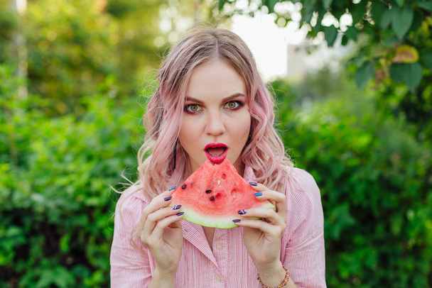 Beautiful young woman with pink hair enjoying watermelon - Foto, imagen