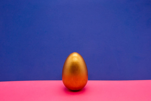 one gold Easter eggs on blue and pink background - Fotoğraf, Görsel