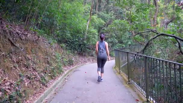 Menina mista bonita em roupas de treino em uma colina caminha através da ponte 4k
 - Filmagem, Vídeo