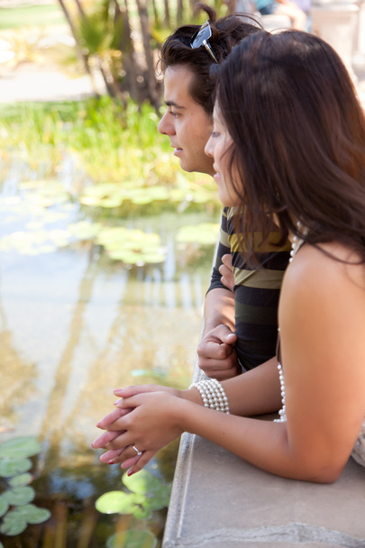 Atractiva pareja hispana pasa por alto estanque juntos al aire libre
. - Foto, imagen