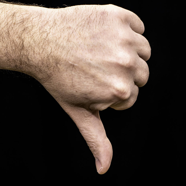 palma masculina apretada en un pulgar del puño apuntando hacia abajo en el gesto de fondo negro aversión
 - Foto, imagen