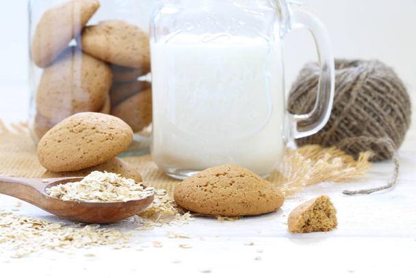 Oatmeal cookies with milk on a white wooden background - Photo, image