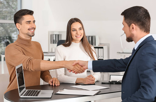 Bank manager shaking hands with couple in office - Photo, image