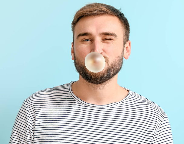 Funny man with chewing gum on color background - Photo, Image