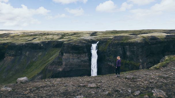 アイスランドのハイフォス滝を見下ろす崖の上に立つ女性 - 写真・画像