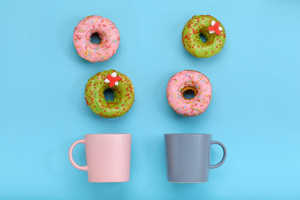Ein Becher, aus dem süße Donuts auf blauem Hintergrund herausfliegen. Süßigkeiten und Kaffee Donuts Konzept. Farbe auf blau. mock up für Design. Kopierraum. - Foto, Bild
