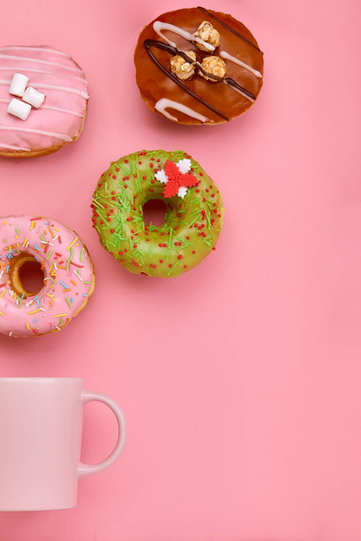 Ein Becher, aus dem süße Donuts auf rosa Hintergrund herausfliegen. Süßigkeiten und Kaffee Donuts Konzept. farbig auf rosa. mock up für Design. Kopierraum. - Foto, Bild