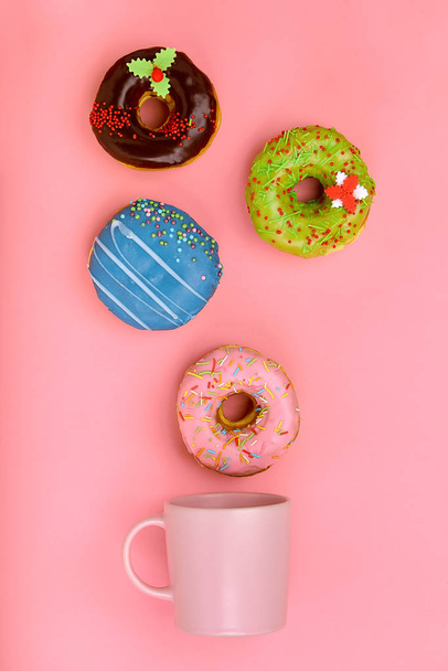 Кружка, из которой вылетают сладкие пончики, на розовом фоне. Концепция сладких и кофе пончиков. цветной на розовом. Макет для дизайна. Копирование пространства
. - Фото, изображение
