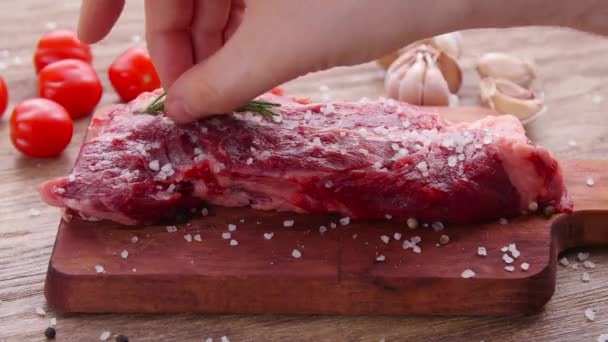 rohes Frischfleisch-Steak mit Kräutern und Gewürzen auf rustikalem Hintergrund - Filmmaterial, Video