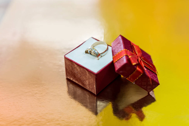 Свадебные кольца в красной коробке подарок на золотом фоне
 - Фото, изображение