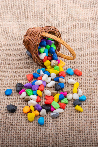 Basket of colorful pebbles spill on canvas background - Photo, Image
