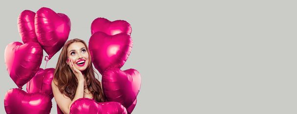 Young model woman having fun and holding pink heart balloons  - Valokuva, kuva