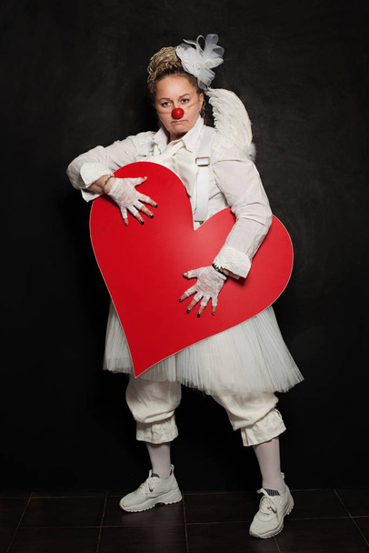 Mujer payaso posando con corazón rojo, retrato de estudio
 - Foto, Imagen