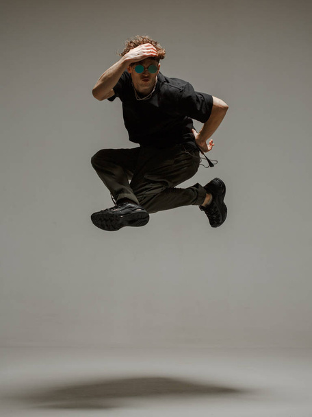 Guy dancing contemporary dance in studio. Neutral grey background. Acrobatic bboy dancer. - 写真・画像