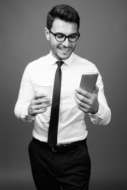 Studioaufnahme eines jungen, gut aussehenden hispanischen Geschäftsmannes vor grauem Hintergrund in Schwarz-Weiß - Foto, Bild