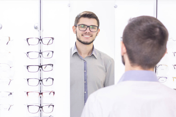 healthcare, people, vision and vision concept. men smiling trying on glasses in the store. - Фото, зображення