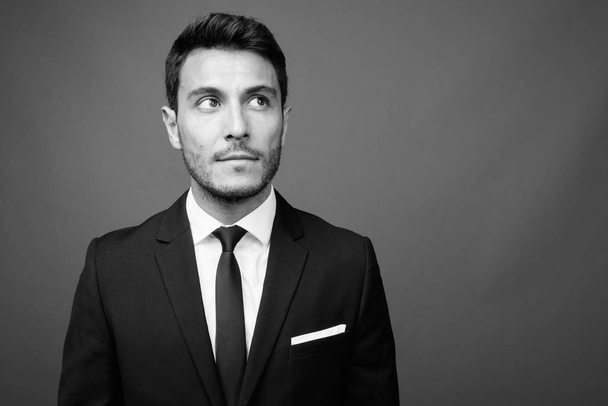 Estudio de un joven empresario hispano guapo con traje sobre fondo gris en blanco y negro - Foto, imagen